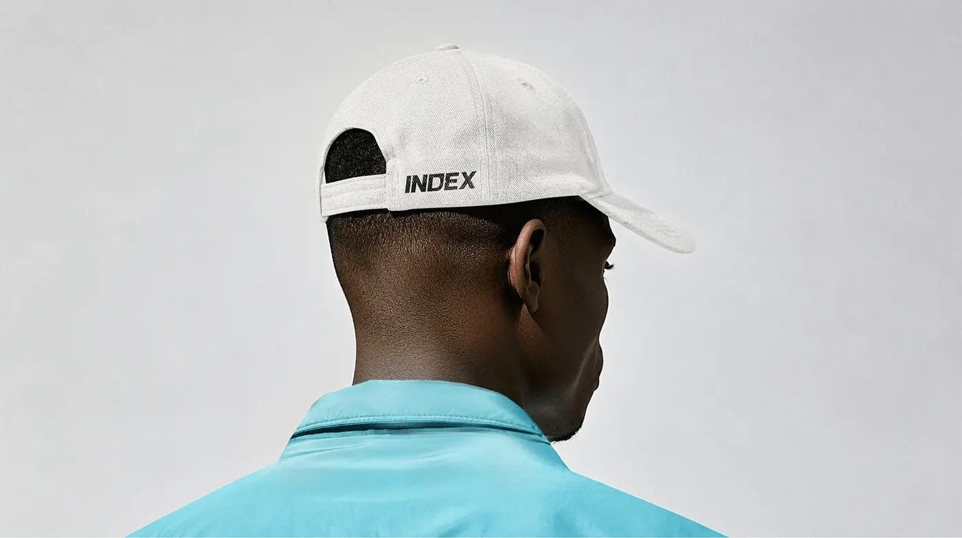 White cap with the INDEX logo, worn with a turquoise shirt